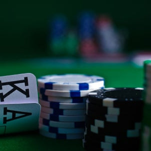 A close-up of poker chips and two playing cards, showing a King and an Ace, on a green table.